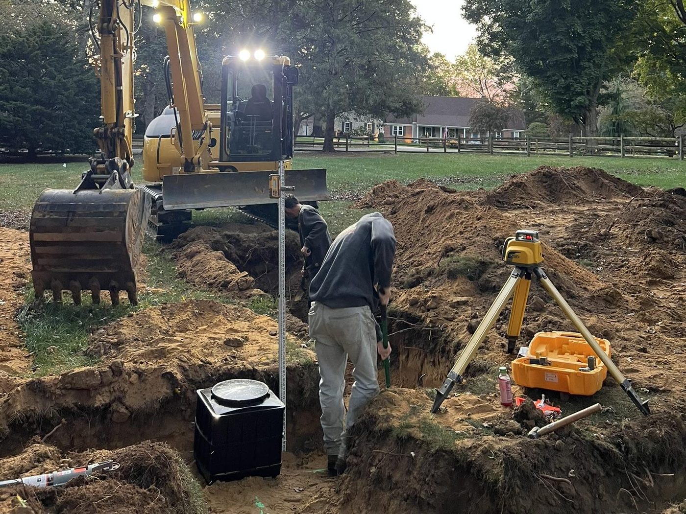 Septic system installation in progress with excavator at dusk