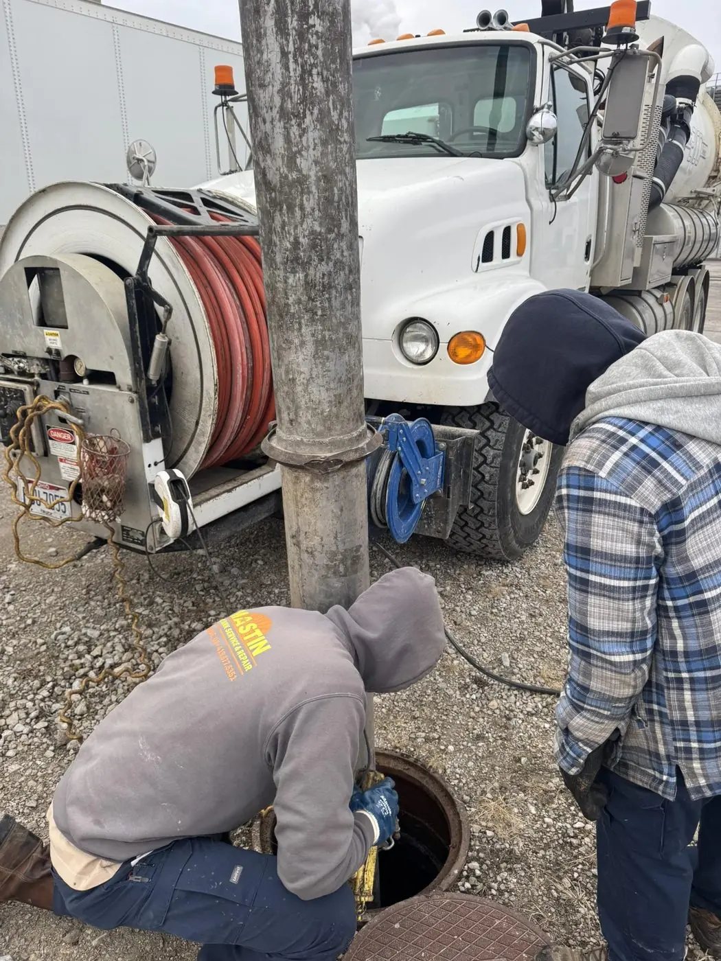 High-pressure jetter cleaning a storm structure manhole